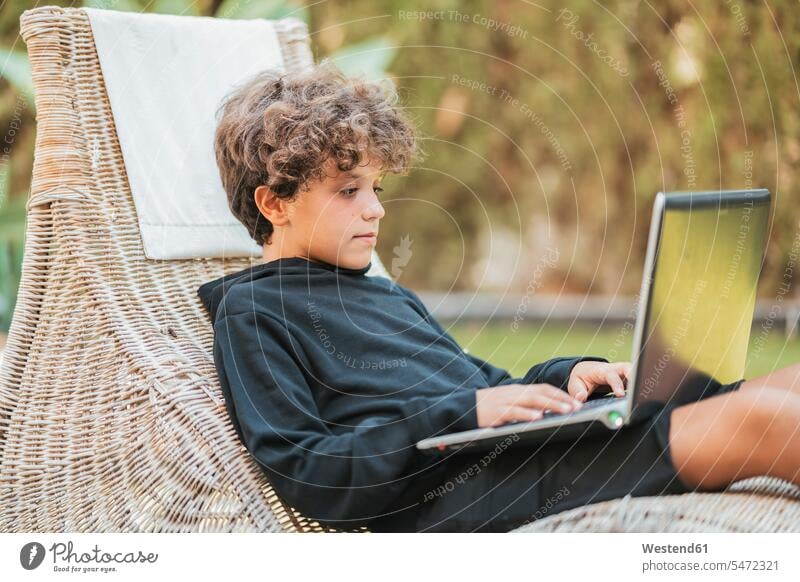 Entspannter Junge mit Laptop im Aufenthaltsraum im Garten Leute Menschen People Person Personen Europäisch Kaukasier kaukasisch Südeuropäisch 1 Ein ein Mensch
