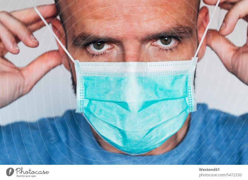 Porträt eines Mannes mit Maske Koepfe Köpfe Gesichter braunaeugig braunes Auge braunäugig T-Shirts fürchten ängstigen Gesundheit Gesundheitswesen medizinisch