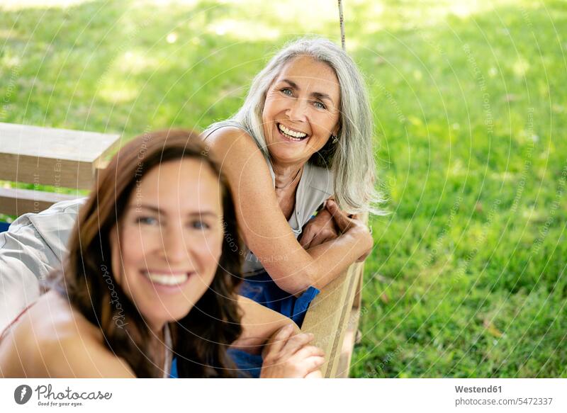 Porträt von zwei glücklichen Frauen entspannen auf einem hängenden Bett im Garten entspannt entspanntheit relaxt Glück glücklich sein glücklichsein Betten