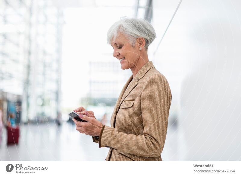 Lächelnde ältere Geschäftsfrau, die ein Mobiltelefon benutzt Geschäftsfrauen Businesswomen Businessfrauen Businesswoman Frau weiblich Frauen Seniorin