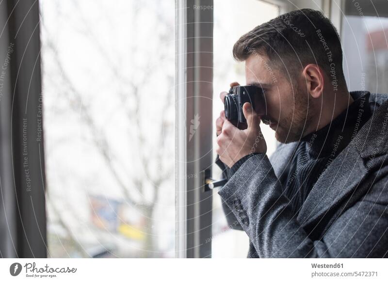 Junger Mann beim Fotografieren am Fenster Leute Menschen People Person Personen Geheimagent Geheimagenten Spione Spitzel Job Berufe Berufstätigkeit