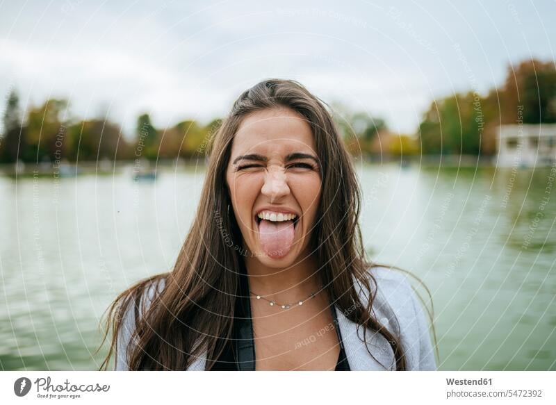 Bildnis einer Frau an einem See mit herausgestreckter Zunge Touristen freuen witzig Frechheit Muße humorvoll lustig spaßig Spass spassig Spässe Späße auf Achse