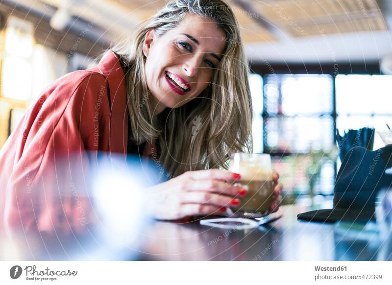Porträt einer glücklichen Frau, die einen Drink am Tresen einer Bar zu sich nimmt weiblich Frauen Theke Theken Bars Getränk Getraenk Getränke Getraenke Portrait