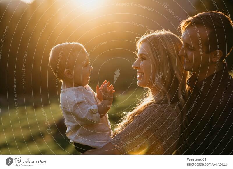 Glückliche Familie mit kleinem Sohn bei Sonnenuntergang im Freien Leute Menschen People Person Personen Europäisch Kaukasier kaukasisch Gruppe von Menschen
