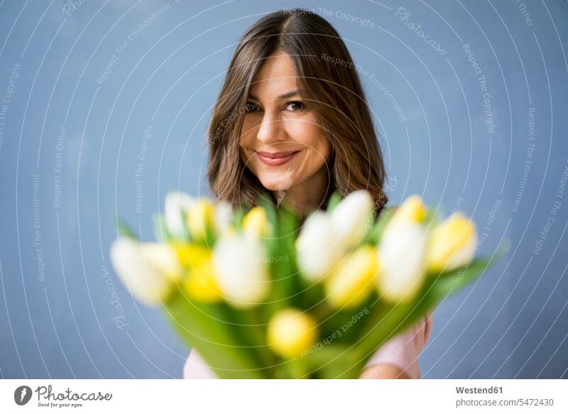 Porträt einer lächelnden Frau mit einem Tulpenstrauss Portrait Porträts Portraits Tulipa Liliaceae Tulipa weiblich Frauen halten Blumenstrauß Bouquet