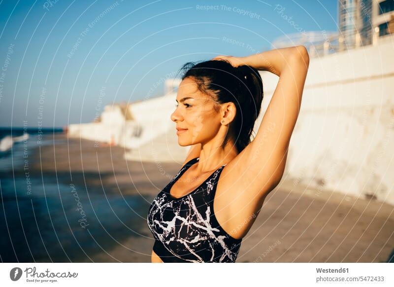 Frau beim Training, Arm strecken am Strand freuen Glück glücklich sein glücklichsein zufrieden Muße beweglich Biegsamkeit Anreiz Ansporn Antrieb motivieren