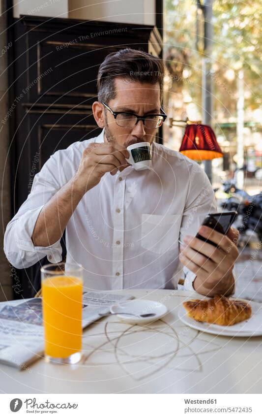 Geschäftsmann beim Frühstück in einem Café und Überprüfung Handy Businessmann Businessmänner Geschäftsmänner checken Cafe Kaffeehaus Bistro Cafes Cafés