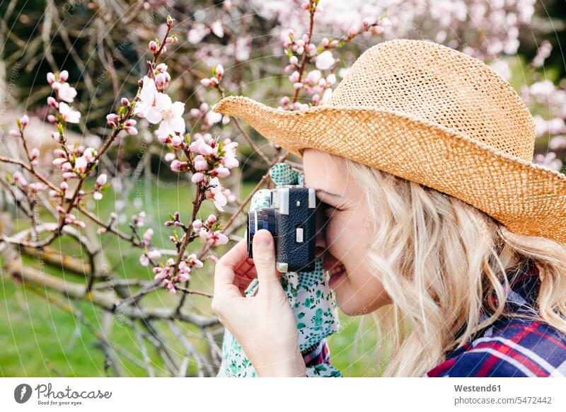 Junge Frau mit Strohhut fotografiert im Garten mit einer alten Kamera Bilder Bildnis Fotos Hüte Strohhuete Strohhüte Gaerten Gärten Leute Menschen People Person