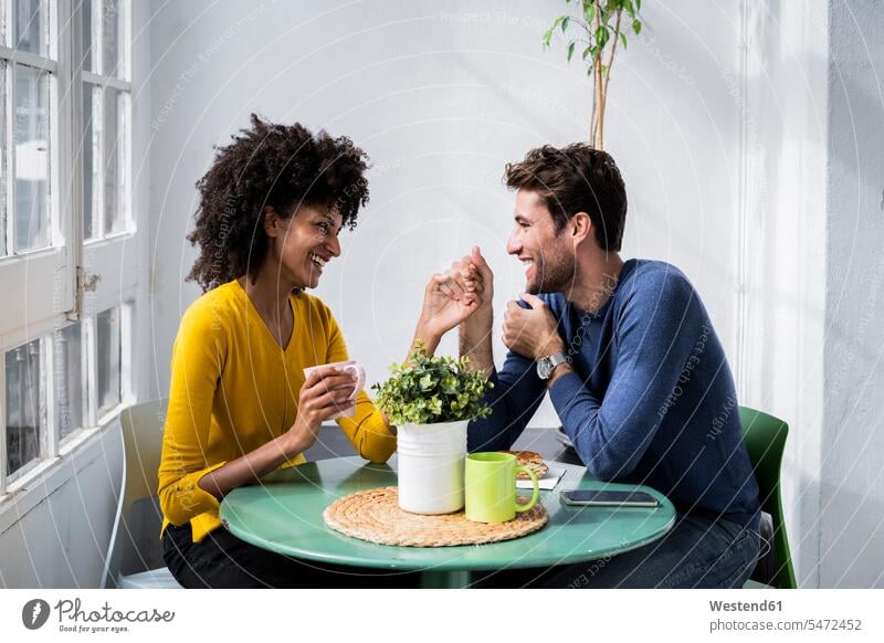 Glücklich zärtliches Paar sitzt am Tisch zu Hause Tische entspannen relaxen Flirt sitzend entspanntheit relaxt freuen geniessen Genuss glücklich sein