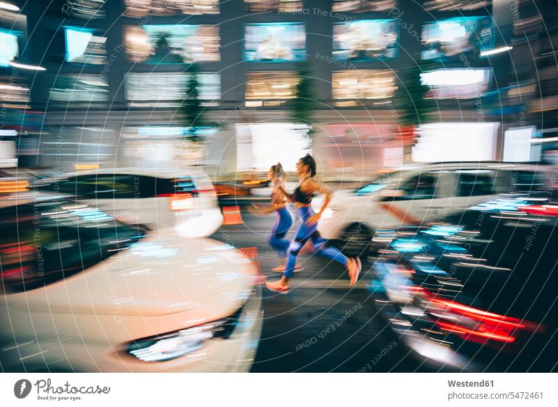 Langzeitbelichtung Foto von zwei Frauen laufen durch die Straßen in der Stadt in der Nacht Freunde Kameradschaft Freundin KFZ Verkehrsmittel Automobil Autos PKW