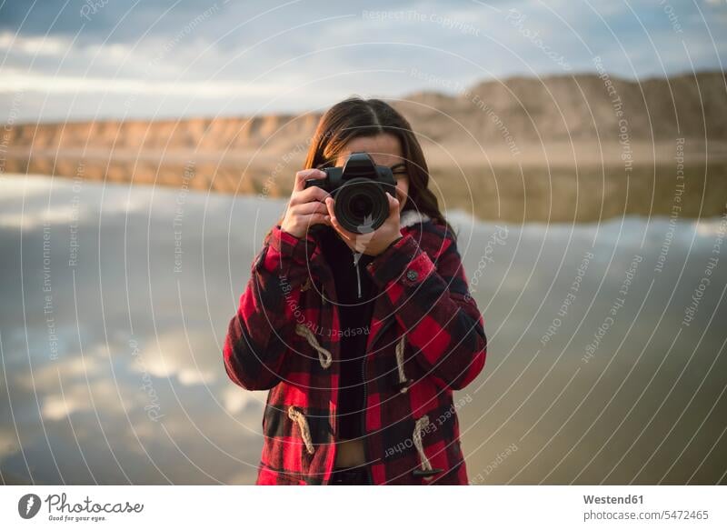 Junge Frau nimmt Bild mit Kamera am Strand Beach Straende Strände Beaches Fotoapparat Fotokamera fotografieren weiblich Frauen Erwachsener erwachsen Mensch