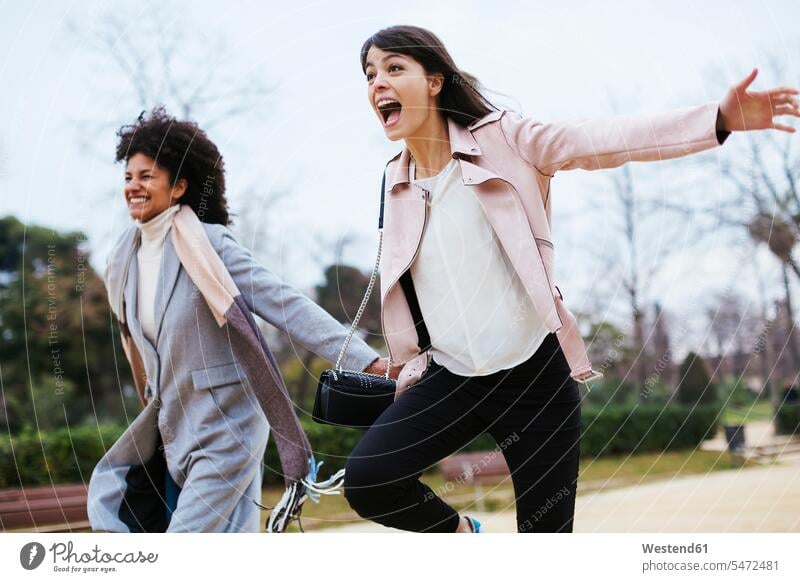 Spanien, Barcelona, zwei überschwängliche Frauen laufen im Stadtpark weiblich ausgelassen Ausgelassenheit Park Parkanlagen Parks staedtisch städtisch glücklich