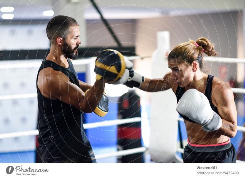 Boxerin beim Sparring mit ihrem Trainer im Fitnessstudio Uebungsleiter Übungsleiter ausüben trainieren fit gesund Gesundheit Muße Kampfkunst Kampfsportart