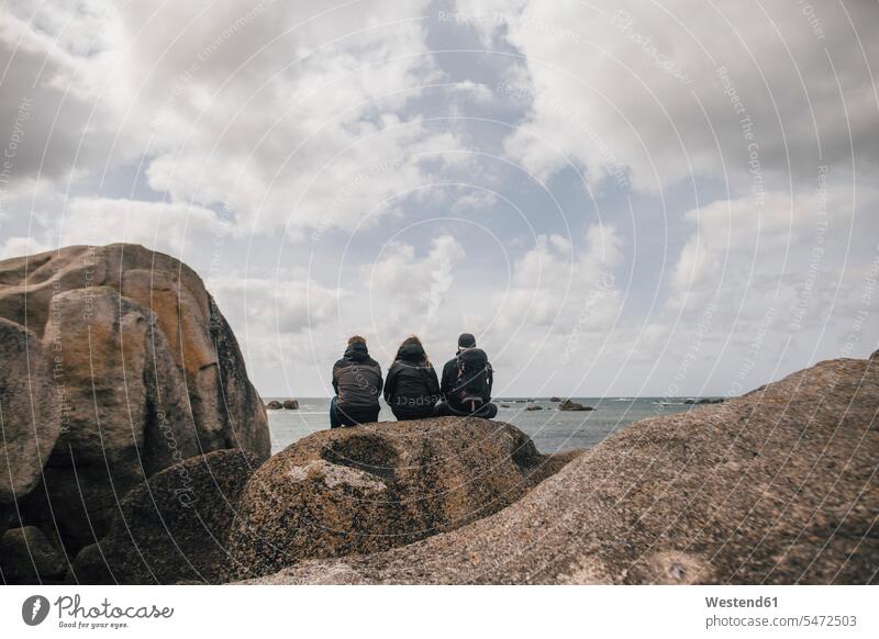 Frankreich, Bretagne, Meneham, Freunde sitzen auf einer Felsformation an der Küste Felsen sitzend sitzt Küstenlandschaft Felsengruppe Gesteinsformation