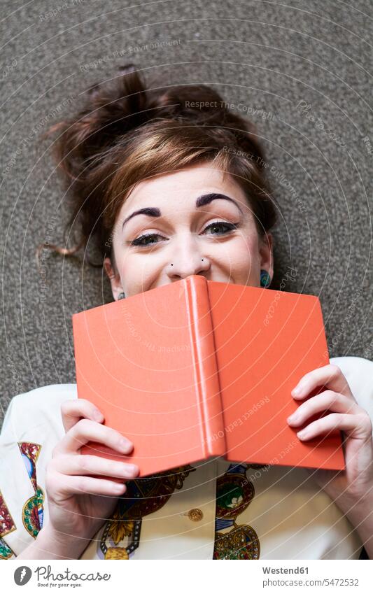 Studentin beim Lesen eines Buches in einer öffentlichen Bibliothek liegen Portrait Frau lesen Erwachsener Mensch Akademische Bildung Nasenpiercing Bluse