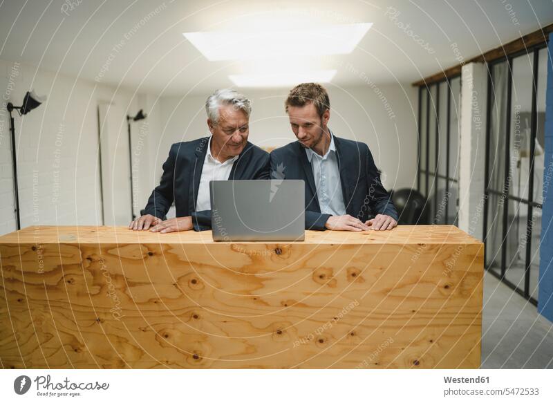 Zwei Geschäftsleute arbeiten am Tresen, schauen auf einen Laptop, lächeln Generation Job Berufe Berufstätigkeit Beschäftigung Jobs geschäftlich Geschäftsleben