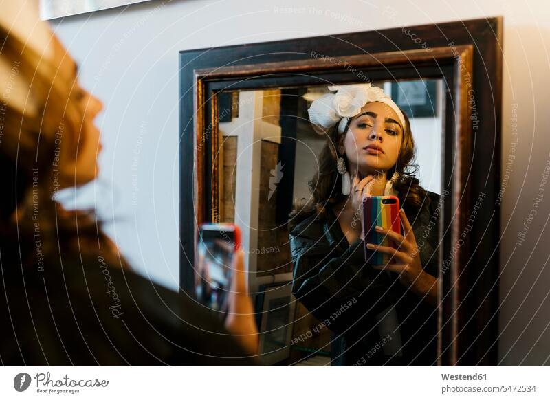Weiblicher Teenager, der ein Selfie mit seinem Smartphone macht und in den Spiegel schaut Farbaufnahme Farbe Farbfoto Farbphoto Innenaufnahme Innenaufnahmen