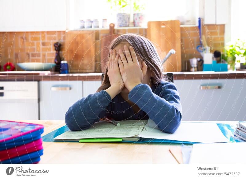 Mädchen macht zu Hause in der Küche Hausaufgaben, Hände auf dem Gesicht lernen sitzen Langeweile Zuhause Stress Portrait Schülerin Problem Textfreiraum