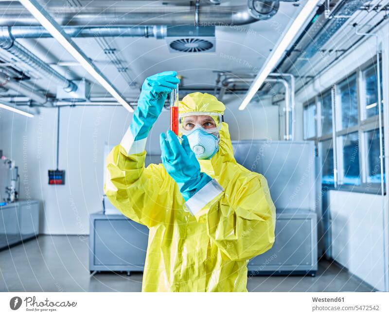 Chemikerin bei der Arbeit im Industrielabor, Kontrolle des Reagenzglases Chemikanten arbeiten Schutzanzug Schutzanzuege Schutzanzüge Chemielabor