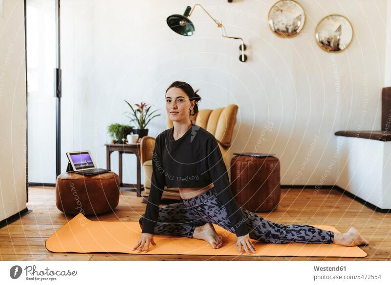 Junge Frau, die zu Hause Yoga praktiziert Stuehle Stühle entspannen relaxen ausüben trainieren Übung zufrieden daheim Fit gesund Gesundheit Technik Technologien