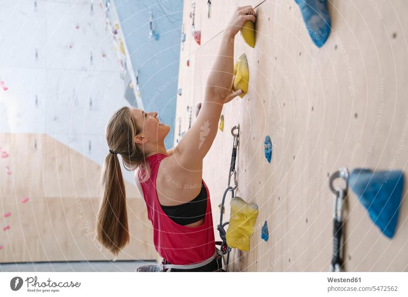 Glückliche Frau beim Klettern an der Wand in einer Kletterhalle (value=0) Leute Menschen People Person Personen Europäisch Kaukasier kaukasisch 1 Ein ein Mensch