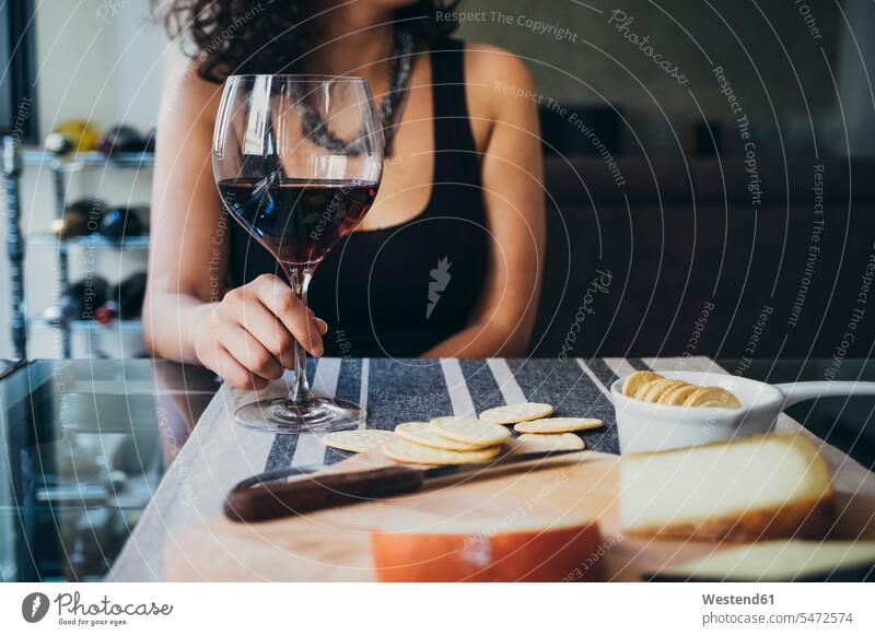 Junge Frau hält Weinglas in der Hand, während sie am Esstisch sitzt Farbaufnahme Farbe Farbfoto Farbphoto Innenaufnahme Innenaufnahmen innen drinnen