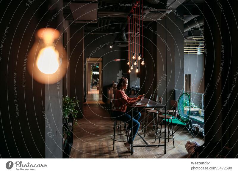 Junge Frau benutzt Laptop und Smartphone in einem Café Job Berufe Berufstätigkeit Beschäftigung Jobs geschäftlich Geschäftsleben Geschäftswelt Geschäftsperson