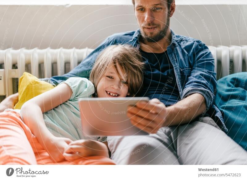 Vater und Sohn schauen zu Hause einen Film auf einem Tablett Tablet Computer Tablet-PC Tablet PC iPad Tablet-Computer Zuhause daheim Papas Väter Vati Vatis