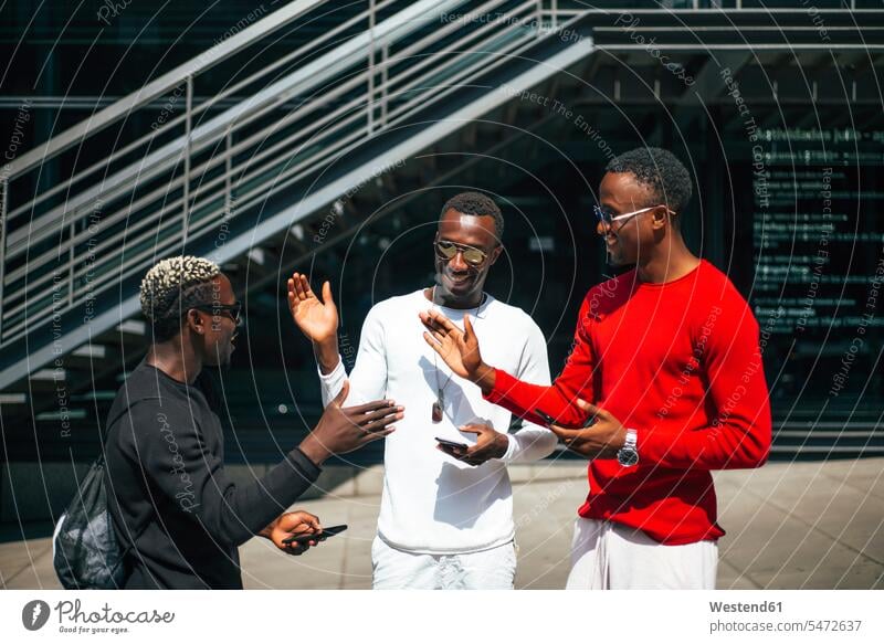 Drei coole junge Männer mit Mobiltelefonen treffen sich in der Stadt Leute Menschen People Person Personen Afrikanisch Afrikanische Abstammung dunkelhäutig