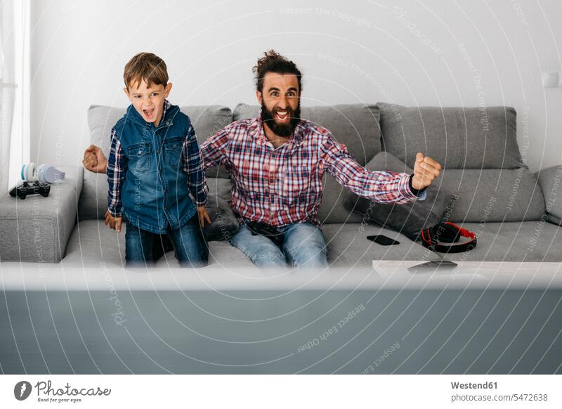 Porträt von Vater und Sohn spielen Computerspiel zusammen auf der Couch Väter Papa Vati Familienvater Papi Gemeinsam Zusammen Miteinander Portrait Porträts