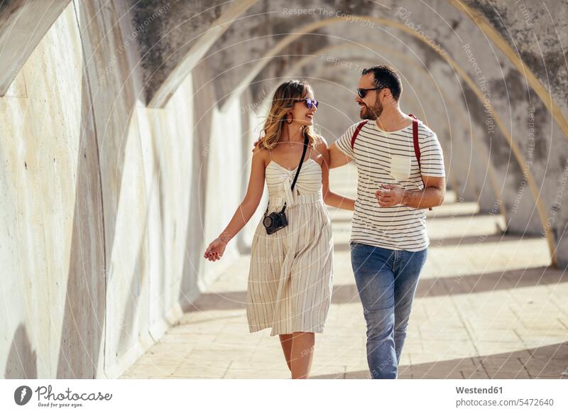 Spanien, Andalusien, Malaga, glückliches Touristenpaar unter einem Torbogen in der Stadt spazierend staedtisch städtisch Durchgang Glück glücklich sein