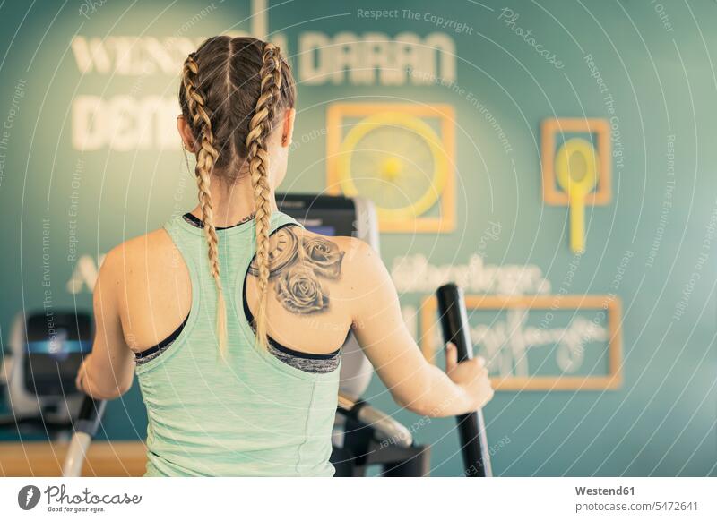 Rückansicht einer jungen Frau, die auf einem Schrittgerät im Fitnessstudio trainiert ausüben trainieren Übung fit gesund Gesundheit Muße Leistungen Individuell