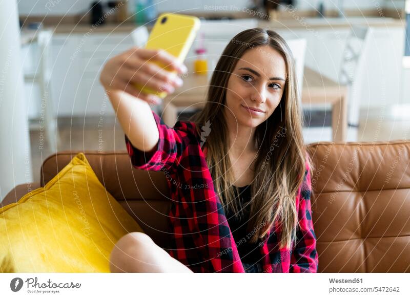 Junge Frau macht ein Selfie auf einer Couch zu Hause Leute Menschen People Person Personen Alleinstehende Alleinstehender Singles Unverheiratete Unverheirateter