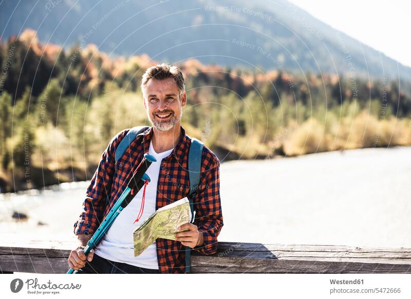 Österreich, Alpen, lächelnder Mann beim Wandern mit Landkarte auf einer Brücke Europäer Europäisch Kaukasier kaukasisch reifer Mann reife Männer 45-50 Jahre