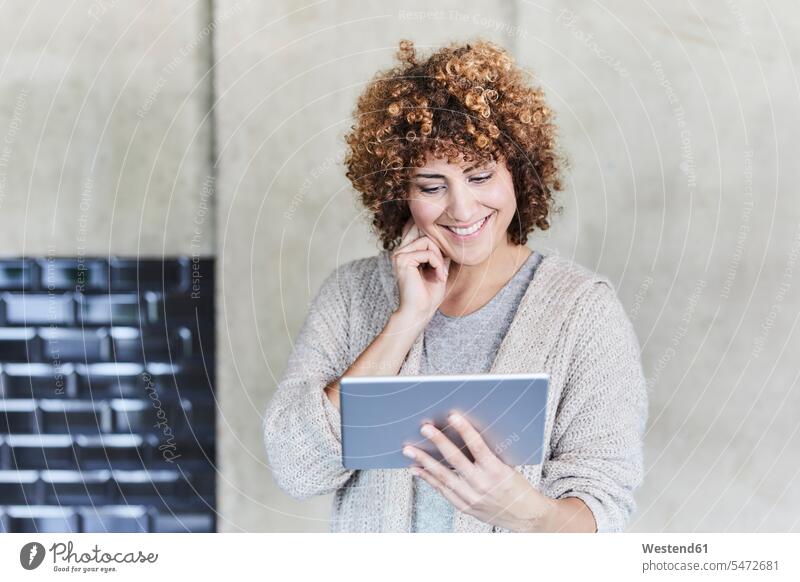Lächelnde Frau mit Tablet an Betonwand Tablet Computer Tablet-PC Tablet PC iPad Tablet-Computer weiblich Frauen lächeln Betonwände Betonwaende Rechner