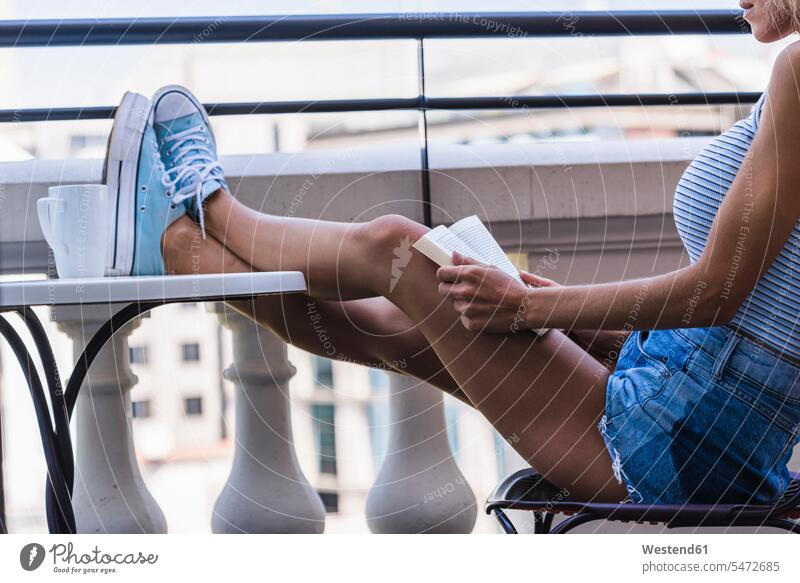 Blonde Frau sitzt auf dem Balkon und liest ein Buch Bücher sitzen sitzend Balkone weiblich Frauen lesen Lektüre Erwachsener erwachsen Mensch Menschen Leute