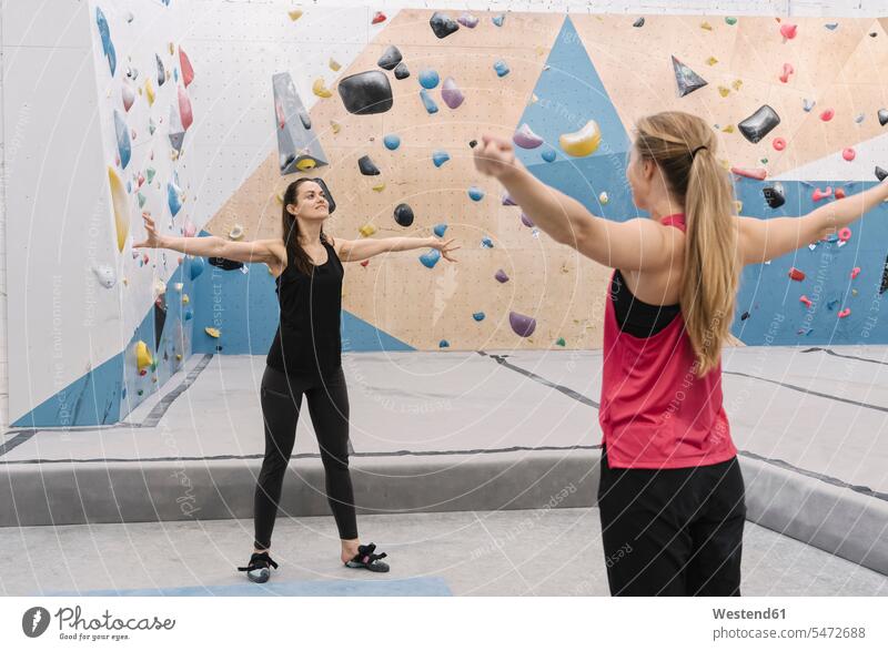 Zwei Frauen machen Dehnungsübungen, bevor sie auf die Wand klettern (value=0) Freunde Kameradschaft Freundin steigen ausüben trainieren Übung Farben Farbtoene