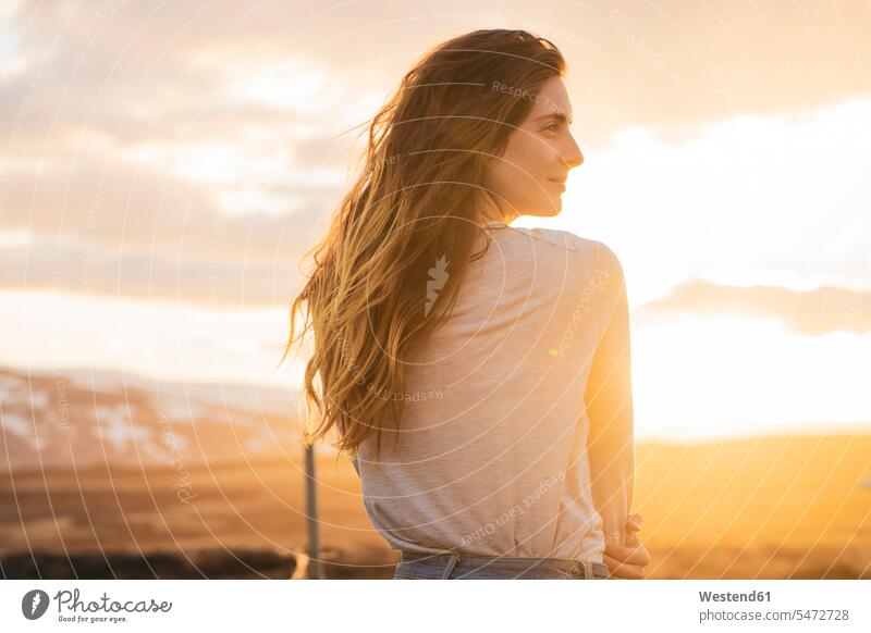 Island, junge Frau bei Sonnenuntergang, Rückansicht Rueckansicht Rückenansicht Rueckenansicht von hinten weiblich Frauen genießen geniessen Genuss lange Haare