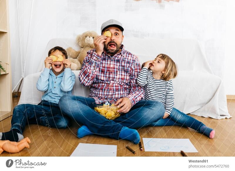 Fahther und Kinder sitzen auf dem Boden und bedecken die Augen mit Kartoffelchips Bilder Bildnis Zeichnungen Kinderzeichnungen Couch Couches Liege Sofas Papiere
