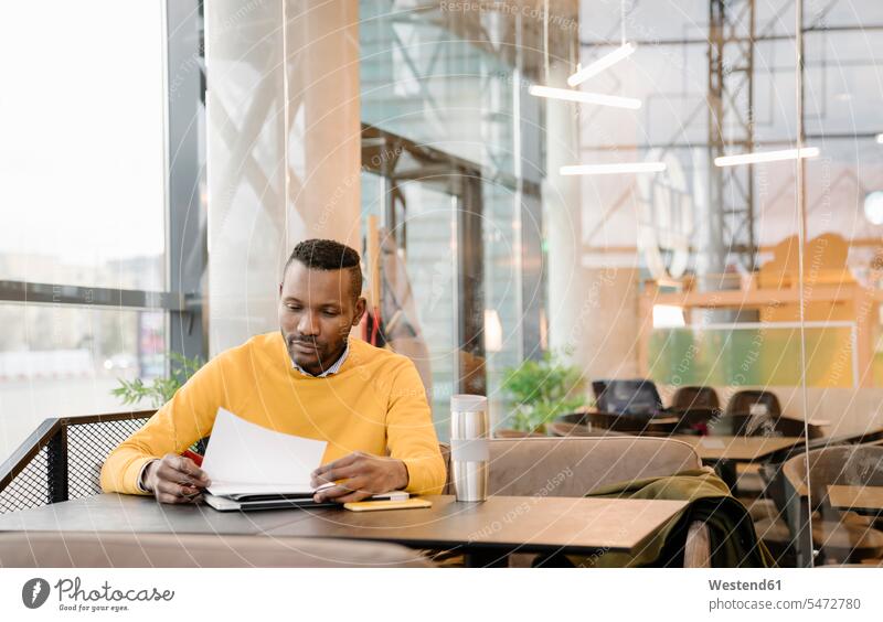 Mann mit wiederverwendbarem Becher beim Lesen von Dokumenten in einem Cafe Job Berufe Berufstätigkeit Beschäftigung Jobs geschäftlich Geschäftsleben