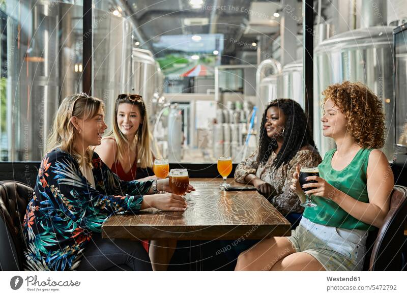Weibliche Freunde, die sich in einer Kneipe treffen Kameradschaft Freundin Gläser Trinkglas Trinkgläser Biergläser Tische Holztische sitzend sitzt reden