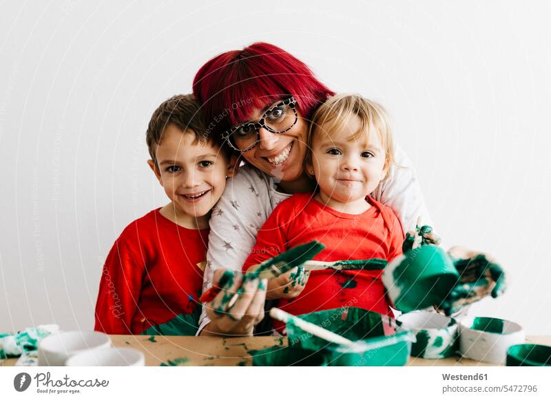 Mutter mit ihren Kindern bastelt zu Hause und malt mit Grün Leute Menschen People Person Personen Europäisch Kaukasier kaukasisch Südeuropäisch Kids Bub Buben