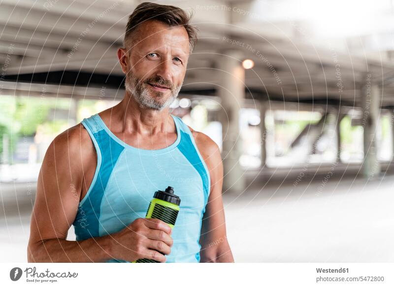 Sportlicher Mann mit Trinkflasche Glück glücklich sein glücklichsein zufrieden stehend steht Muße Leistungen Fit gesund Gesundheit Lebenstil Lifestyles Anreiz