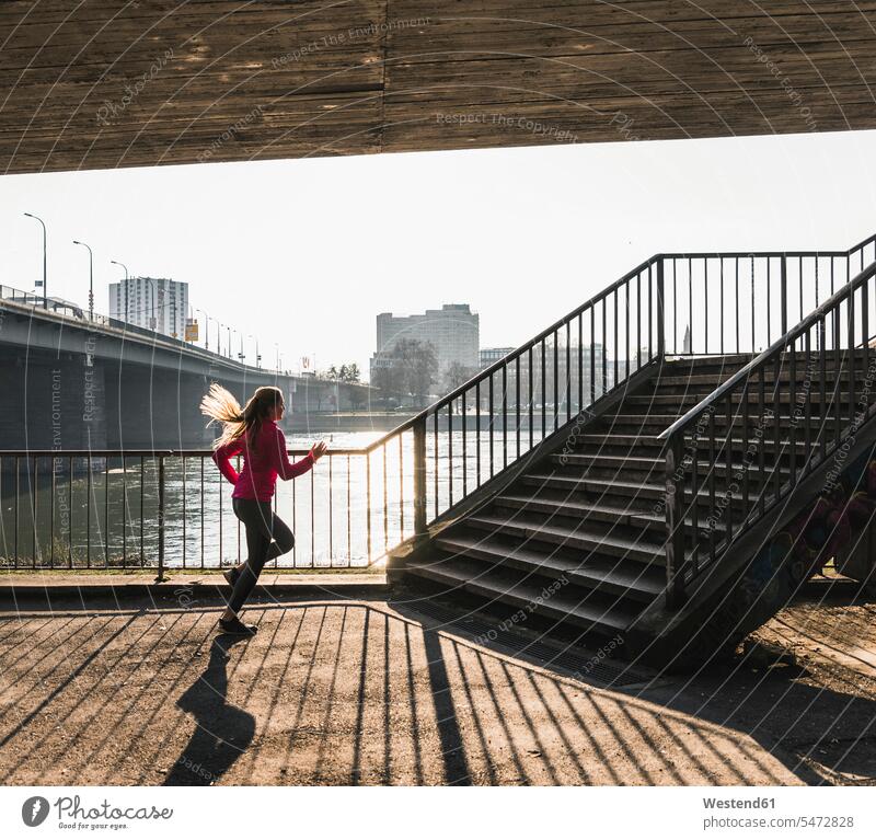 Junge Frau rennt zu einer Treppe an einem Fluss laufen rennen Fluesse Fluß Flüsse weiblich Frauen Joggen Jogging Treppenaufgang Gewässer Wasser Erwachsener