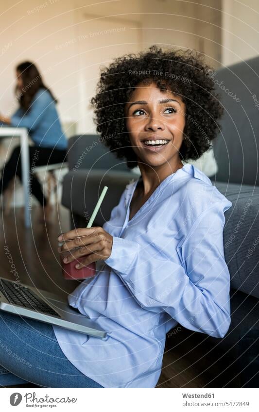 Glückliche Frau mit Softdrink sitzt auf dem Boden mit Laptop Böden Boeden weiblich Frauen Erfrischungsgetränk Erfrischungsgetraenk sitzen sitzend lächeln