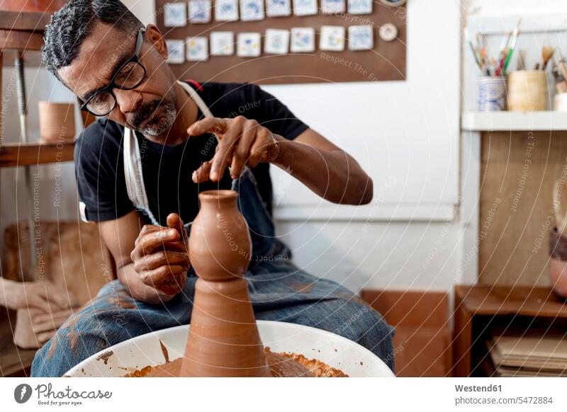 Nahaufnahme eines männlichen Töpfers, der Steingut herstellt, während er in der Werkstatt sitzt Farbaufnahme Farbe Farbfoto Farbphoto Spanien Innenaufnahme