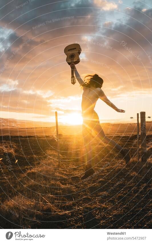 Island, Frau springt mit Gitarre bei Sonnenuntergang springen hüpfen Freudensprung Luftsprung Abendsonne Luftsprünge einen Luftsprung machen Luftspruenge