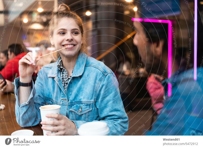 Porträt einer lächelnden jungen Frau in einem Café, die einen jungen Mann ansieht Fensterscheiben Flirt freuen zufrieden Muße Miteinander Zusammen Lifestyles