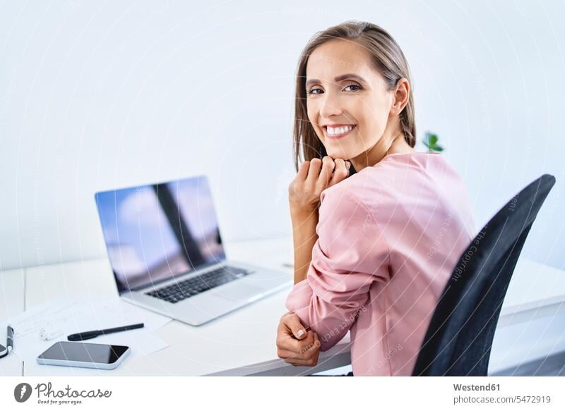 Fröhliche junge Geschäftsfrau lächelt bei der Arbeit im Büro in die Kamera Job Berufe Berufstätigkeit Beschäftigung Jobs geschäftlich Geschäftsleben