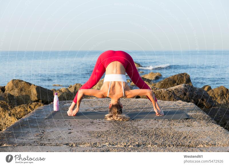 Junge Frau übt Yoga am Strand, macht prasarita padottanasana ausüben trainieren Übung früh Frühe Morgen anpassungsfähig Anpassungsfähigkeit flexibel kräftig